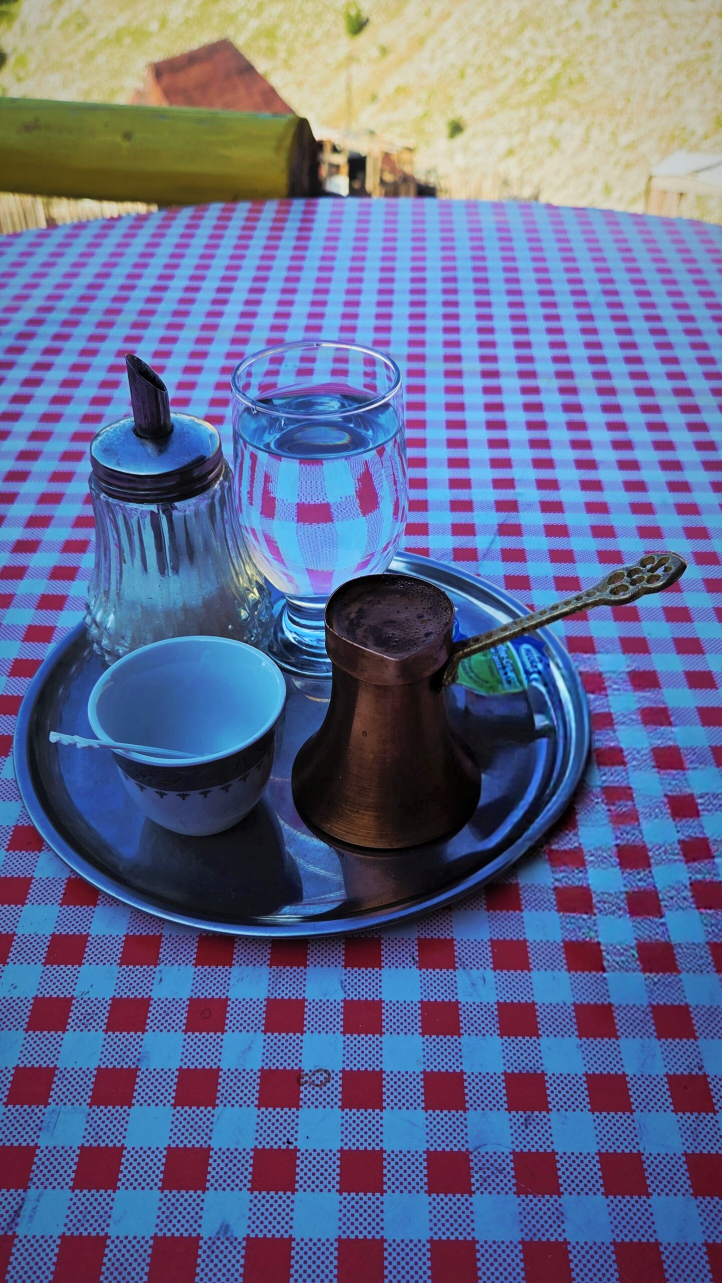 A small traditional džezva coffee pot on a tray, on a terrace in Lukomir